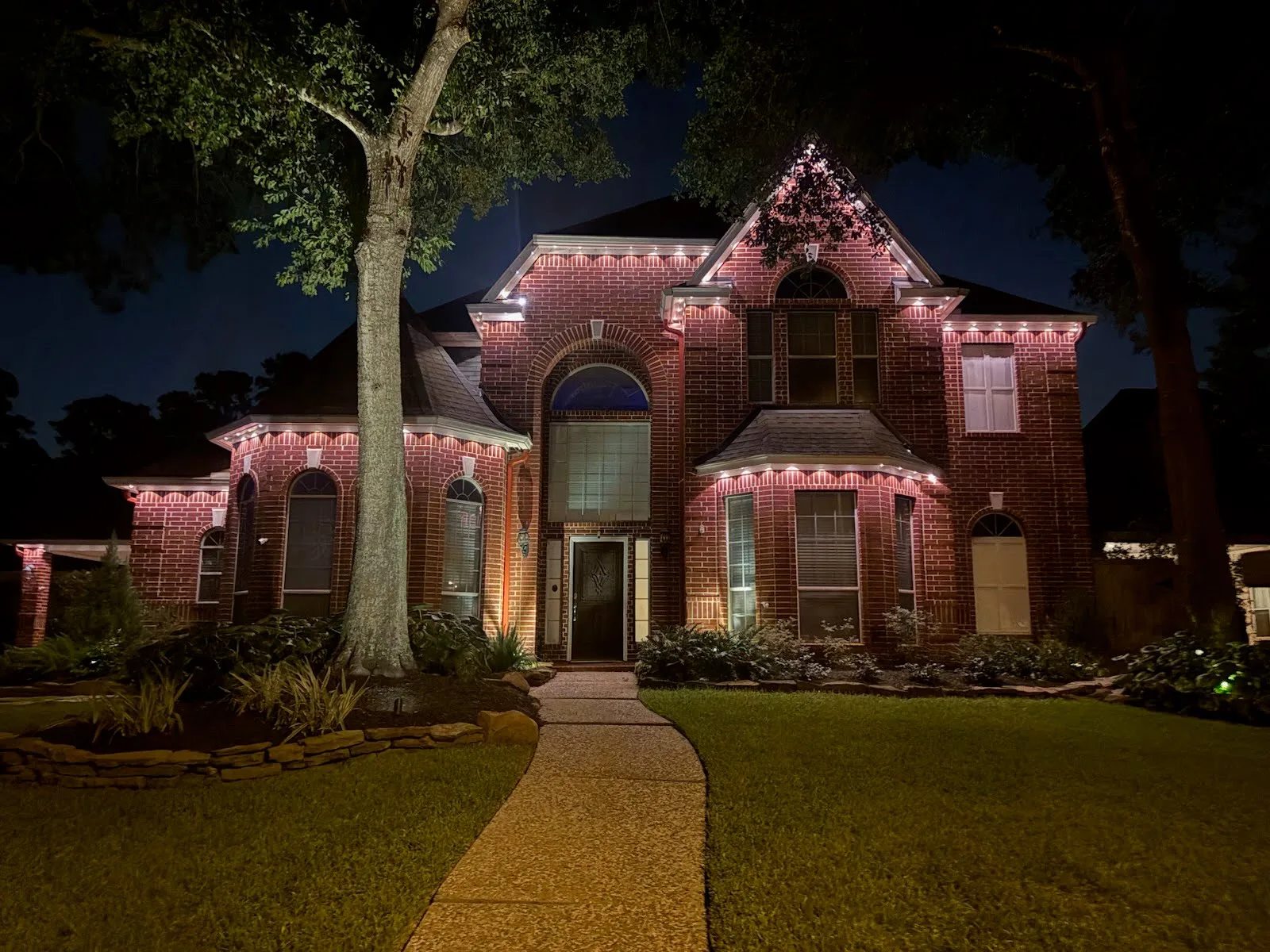 A real BrightSky two-story warm-white permanent roofline lighting installation on a brick home