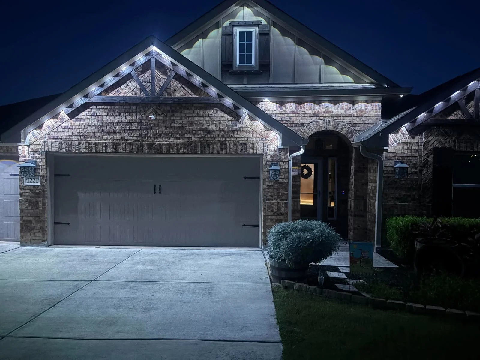 Real BrightSky install — warm-white permanent roofline lighting on a brick home at night
